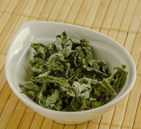 Seasoning dried mint in a white bowl close-up.の写真素材