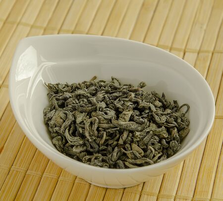 Green leaf tea in a white bowl close-up.の写真素材