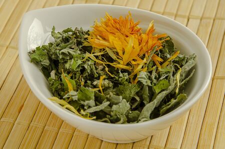 Green grassy loose leaf tea in a white bowl close-up.の写真素材