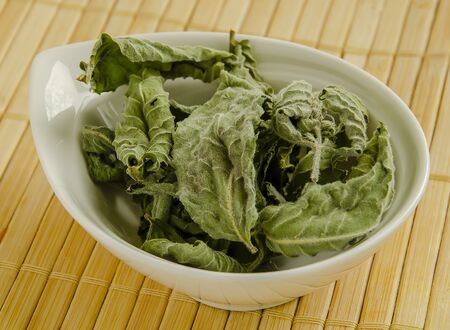 Seasoning dried mint leaf closeup in a white bowl close-up.の写真素材