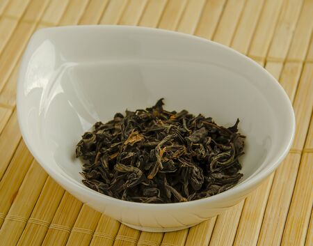 Black loose leaf tea in a white bowl close-up.の写真素材