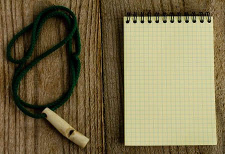 A yellow notebook in a cage and a whistle on the board.の写真素材