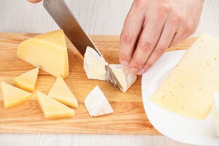 Chef-cook sliced cheeses on a cutting board. Cutting ingredients closeupの写真素材