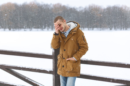 handsome young man stands in a snowy winter parkの写真素材