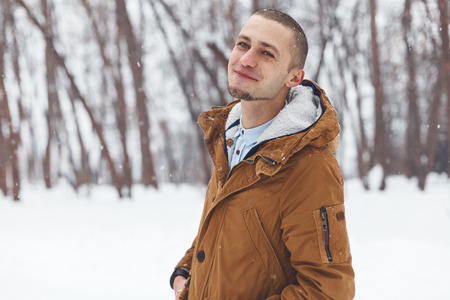 portrait of a young handsome man standing in a winter forestの写真素材