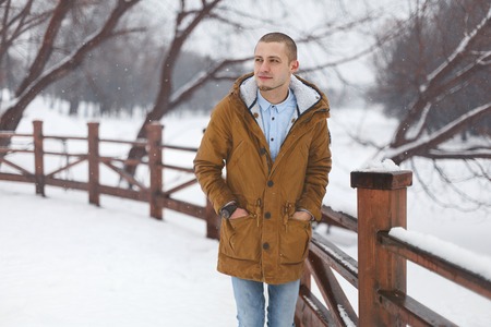 portrait of a young handsome man standing in a winter forestの写真素材