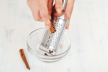 the process of rubbing cinnamon sticks on a grater closeupの写真素材