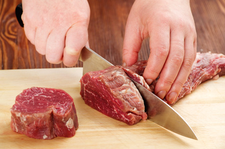 the process of cutting raw beef on a cutting board closeupの写真素材