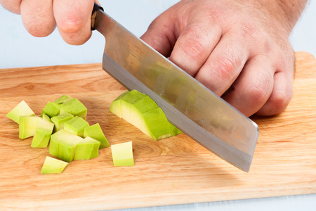 Chef cuts peeled avocado on a cutting board closeupの写真素材