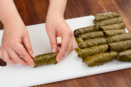 chef prepares cabbage rolls with grape leaves on a cutting board closeupの写真素材