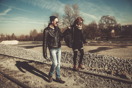 Young and beautiful rock and roll couple walking outdoors on a sunny dayの写真素材