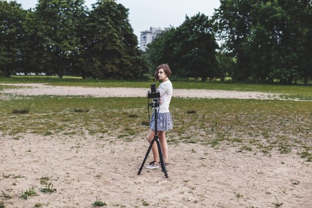 Beautiful girl poses for the camera on a tripod in the outdoor