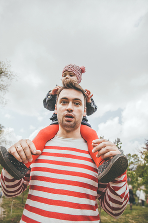 Positive young father walking with her daughter outdoors and laughingの写真素材