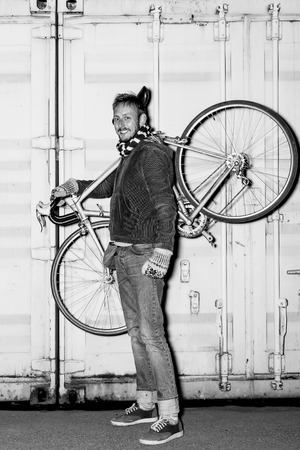 Modern young man posing in an urban environment with the bike on the shoulder at night. Black and white portraitの写真素材