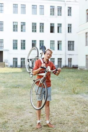 Cheerful man posing with his bicycle on shoulder outdoorsの写真素材