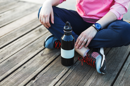 Girl rest on a pier near the lake with metal bottle of waterの写真素材