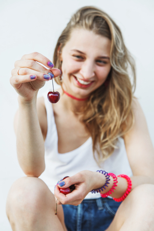 Modern young girl engaged in a healthy diet. Woman holding cherries. Focus on the cherriesの写真素材