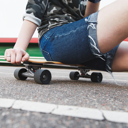 Teenage girl sitting on a longboard at the stadium