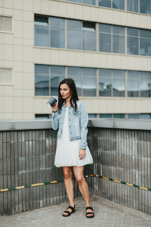 Young attractive brunette woman with a glass of coffee in an urban environmentの写真素材