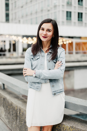 Young attractive brunette woman in a white dress in the urban environmentの写真素材