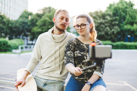 Young married couple with longboards making photo using selfie stickの写真素材