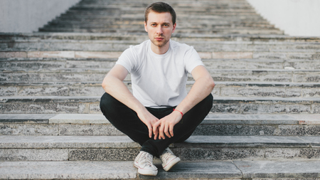 Handsome man sitting on the stairs and think to solve their problemsの写真素材