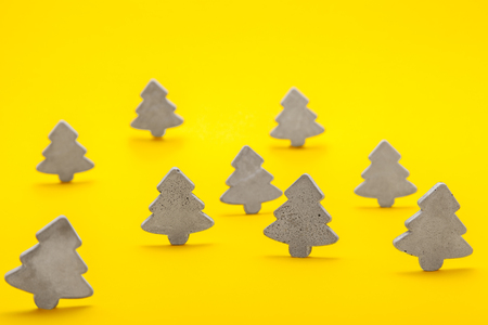 Decorative Christmas trees of concrete stand on a yellow backgroundの写真素材