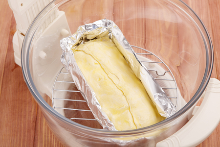 Raw roll of flour dough is placed in the bowl of a grill for cooking. Cooking baking in the convection ovenの写真素材