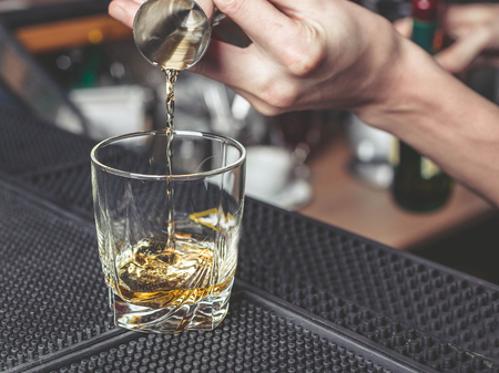 The barman pours whisky in a glassの写真素材