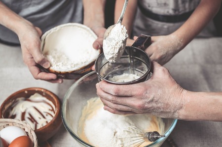 Mothers and childrens hands cook dough for home-made cookies. We cook in kitchen together with children. Happy familyの写真素材