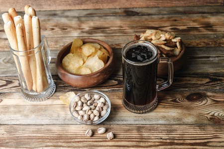 Dark beer in a mug. Snacks for beer on a wooden table. Chips, croutons, bread sticksの写真素材