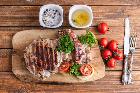 Grilled turkey fillet with spices, herbs and cherry tomatoes on a cutting board.の写真素材