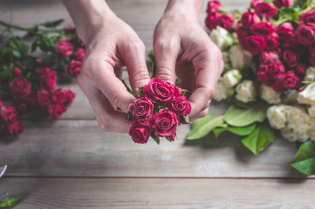 Florist at work. Female hands collect a wedding bouquet of roses. People in the process of workの写真素材
