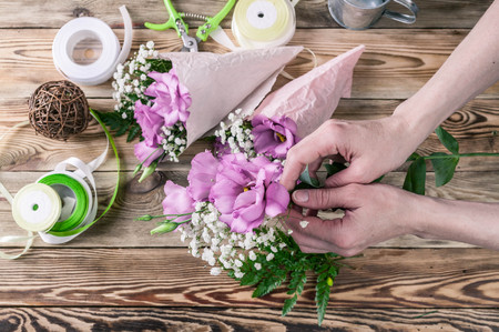 Florist at work. Female hands collect a wedding bouquet. People behind the work concept. The workplace of the florist.の写真素材
