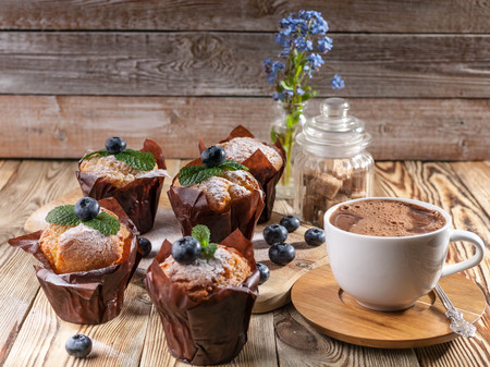 Muffins with blueberries and a cup of hot chocolate on a wooden background. homemade bakingの写真素材
