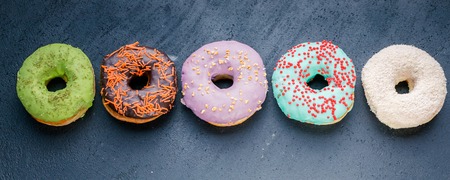 Donuts with a colorful icing on a dark background. Web Food Bannerの写真素材
