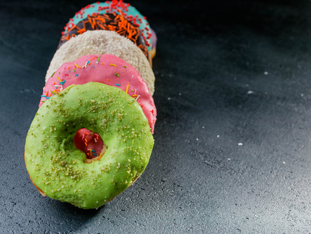 Donuts with a colorful icing on a dark backgroundの写真素材