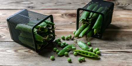Green peas in metal baskets on a wooden background. Close-up. Light toningの写真素材