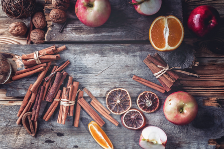 Red apples, oranges, cinnamon, nuts and spices. Recipe for traditional winter mulled wine. Wooden rustic background. Copy place. Top viewの写真素材