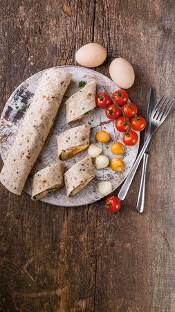 Omelet roll with ham, cheese and herbs. Tasty breakfast. Vertical shotの写真素材