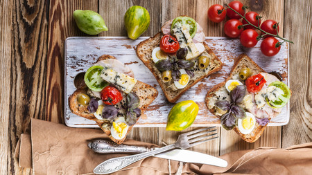 Food banner. Three delicious sandwiches author's cuisine with poultry meat, avocado and tomatoes on a wooden background.の写真素材