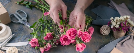 Web banner. Small business concept. Work process of florist. Female hands making wedding bouquet on a dark tableの写真素材