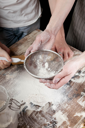 Mom with children preparing the dough for homemade pizza.