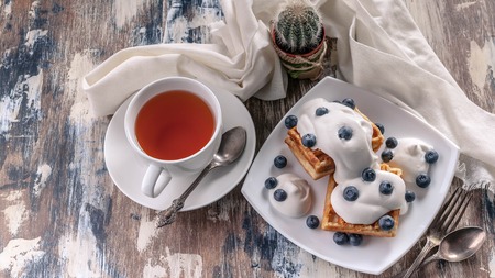 Food banner. Belgian waffles with blueberries, tea in a white cup. Tasty breakfastの写真素材
