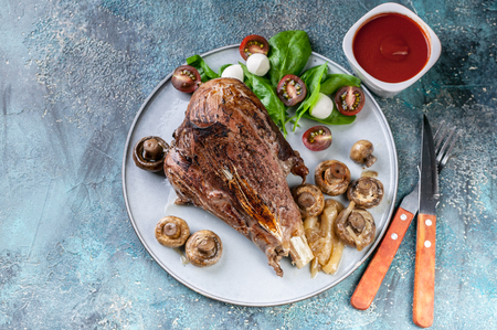 Baked lamb with mushrooms, spices and herbs on a round plate on a concrete background. Halal meat and food. Top viewの写真素材
