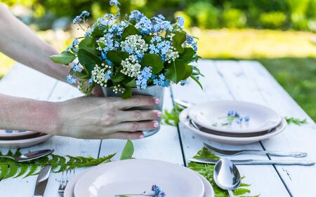 Florist hold elegant bouquet of blue forget-me-not flowers on a white wooden table. Rustic style...