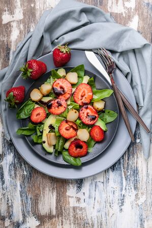 Top view tasty salad with greens, strawberries and smoked cheese. Tasty and healthy food. Vertical shotの写真素材