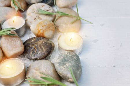 SPA composition. Sea pebbles, bamboo shoots, scented candles, sea salt on a light wooden background. Copy spaceの写真素材