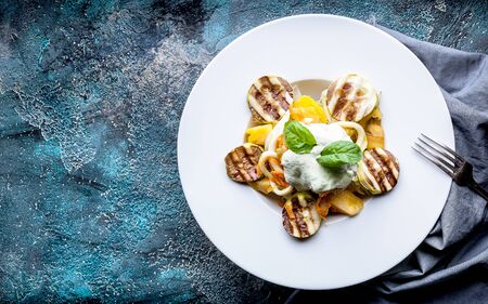 Squid salad, with grilled zucchini vegetables, tomatoes, carrots and arugula sauce. Delicious healthy low-calorie salad. Top view. Copy spaceの写真素材