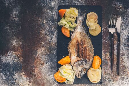 Grilled dorada fish with vegetables close-up. Top view. Copy space